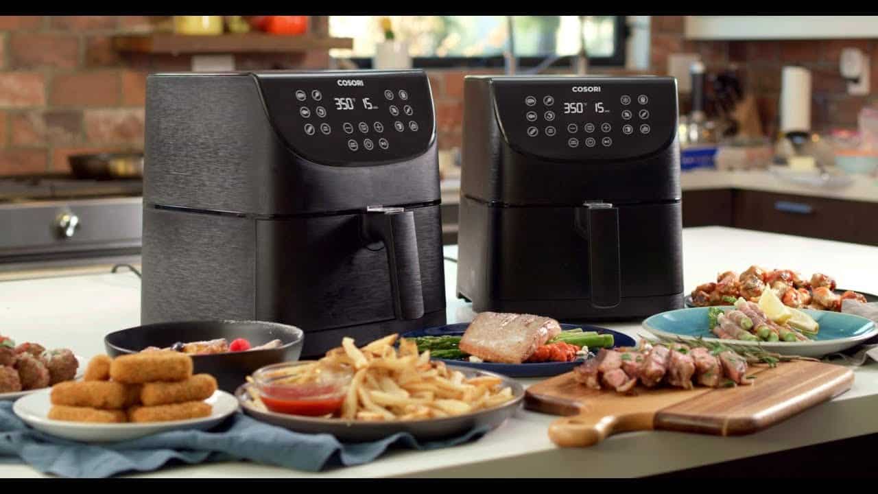 Two air fryers on a countertop with air-fried food in front
